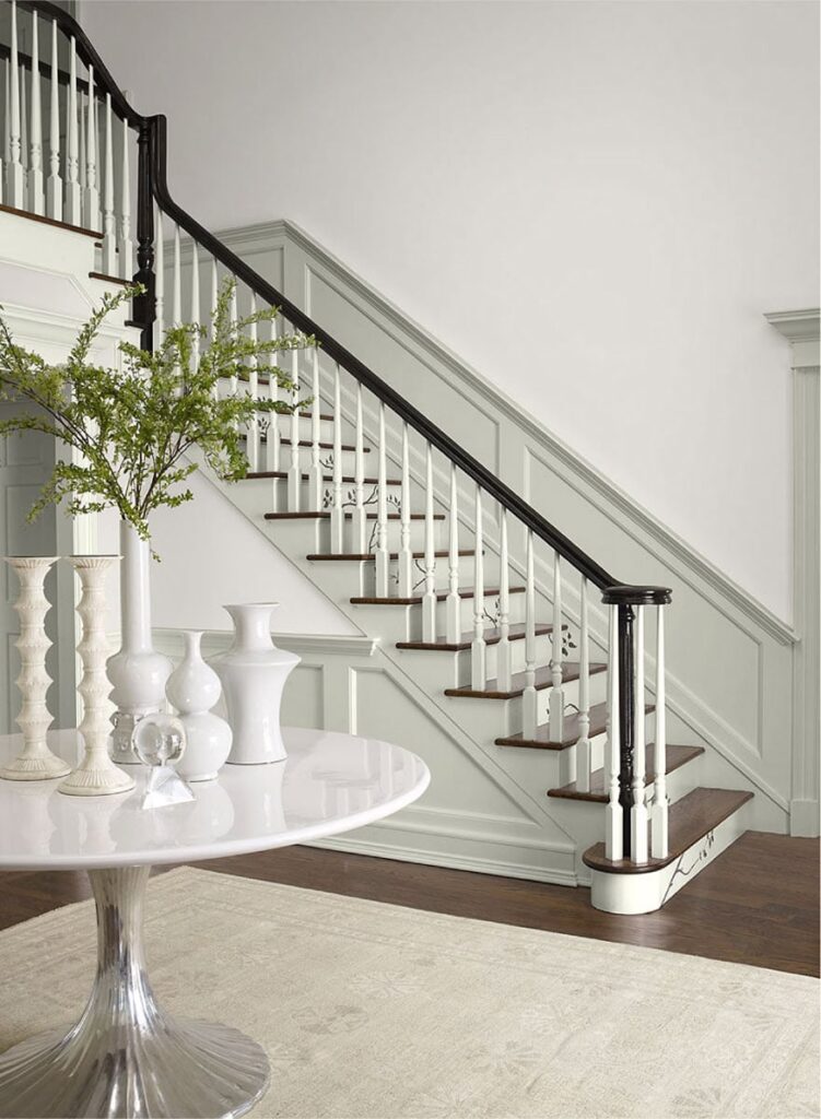 โถงทางเข้าบ้านสีสไตล์คลาสสิก ผนังทาด้วยเฉดสีขาว Lacey Pearl 2108-70 จาก Benjamin Moore จับคู่ักับขอบบัวบันไดสีเทาอ่อน Stonington Gray HC-170 ได้สวยงาม ให้บรรยากาศโปร่งโล่ง สบายตา